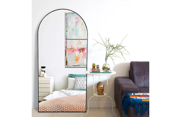 Black framed metal arch mirror styled in bedroom with contemporary furniture