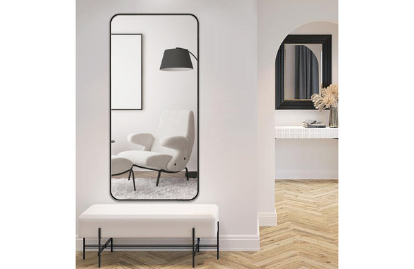 Medium-sized black metal rectangle mirror displayed on wall in a minimal hallway interior.