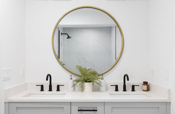 Gold round mirror styled in contemporary bathroom above double sink vanity