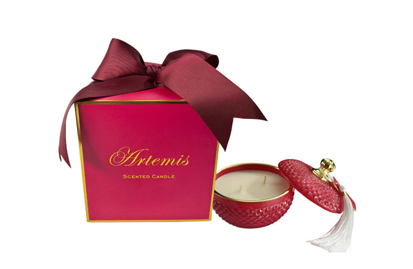 Artemis luxury candle in a textured deep pink glass jar with tassel lid, scented with blood orange and grapefruit, presented in a matching gift box.