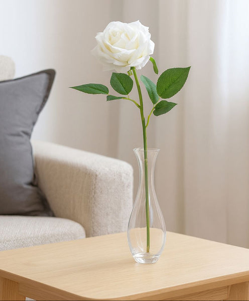White rose in a clear vase on a wooden table with a neutral background