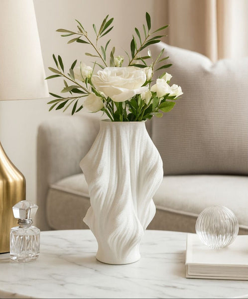White vase with flowers on a marble surface in a living room setting