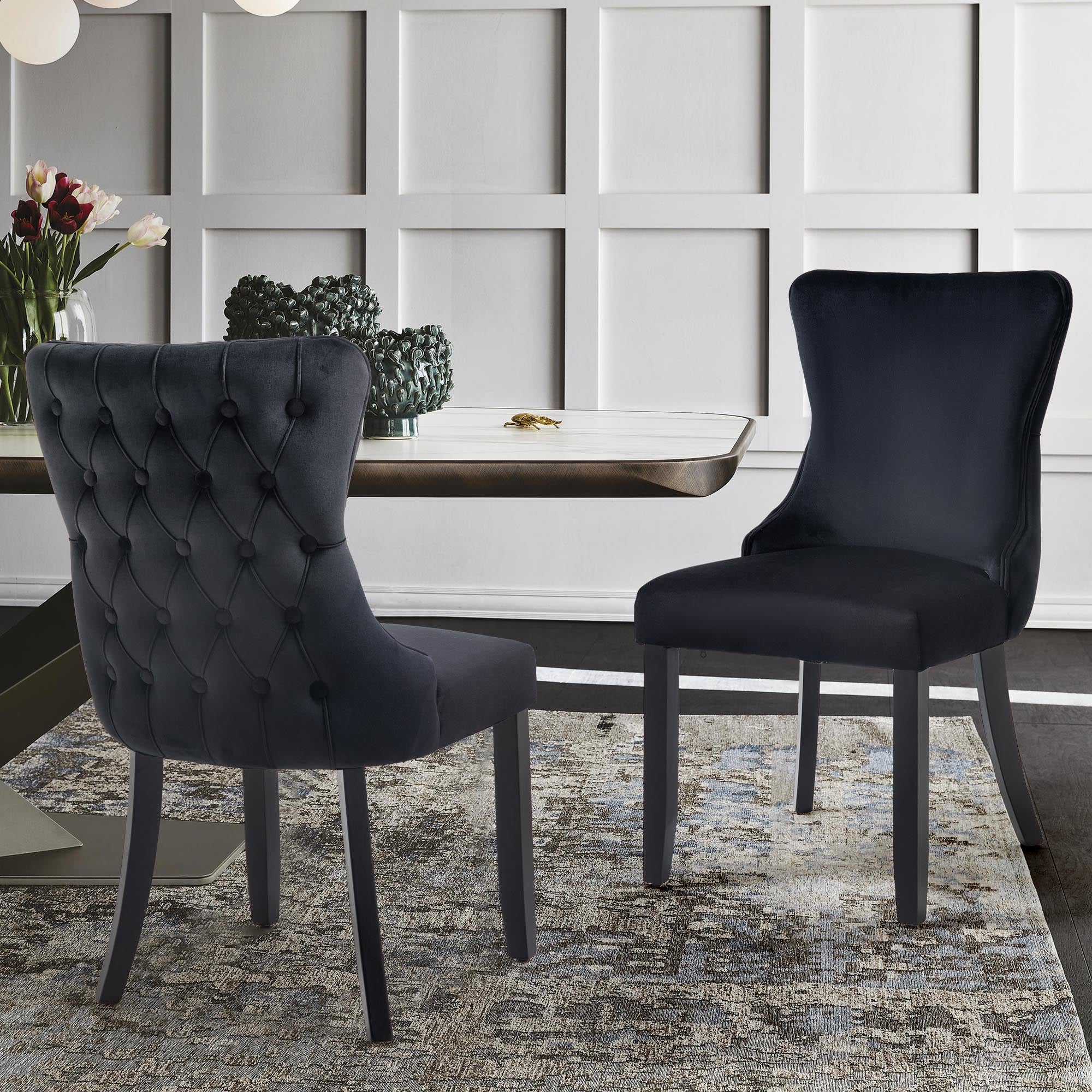 Pair of black velvet Paris dining chairs with tufted backrest in a dining room setup.