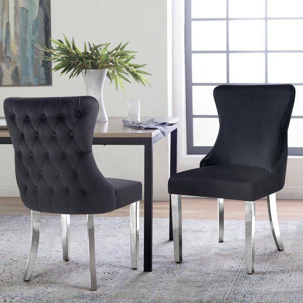 Pair of black velvet Paris dining chairs with polished silver legs in bright dining space.