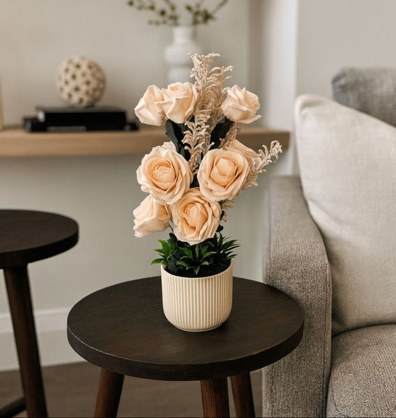 Decorative flower arrangement in a pot on a small round table in a living room.