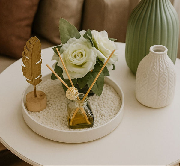 Decorative tray including a vase with flowers and a diffuser.