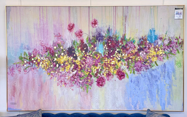 Oversized pink and multi-colour floral canvas wall art with gold frame, mounted above a blue sofa.
