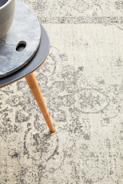 Close-up of Century 977 Silver Rug with detailed patterns beneath a wooden table leg.