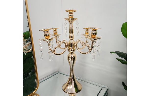 Gold 5-arm candelabra with tall white candles, adding a warm and opulent touch to any décor.
