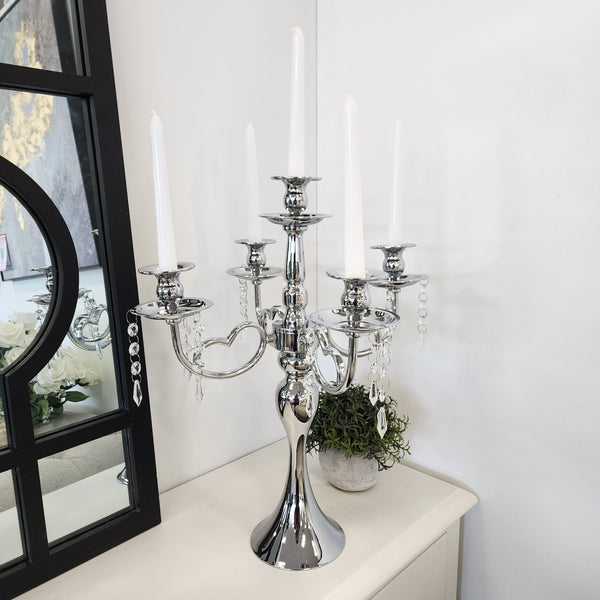 Silver 5-arm candelabra with tall white candles, styled on a sideboard with mirror décor.