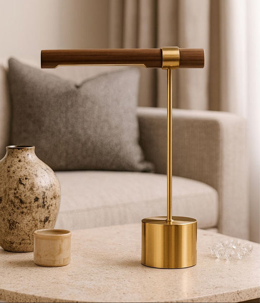 Gold lamp on a table with a vase and small cup in a room setting