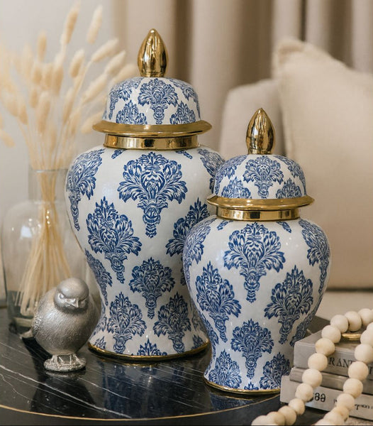 Decorative blue and white jars with gold lids on a table.
