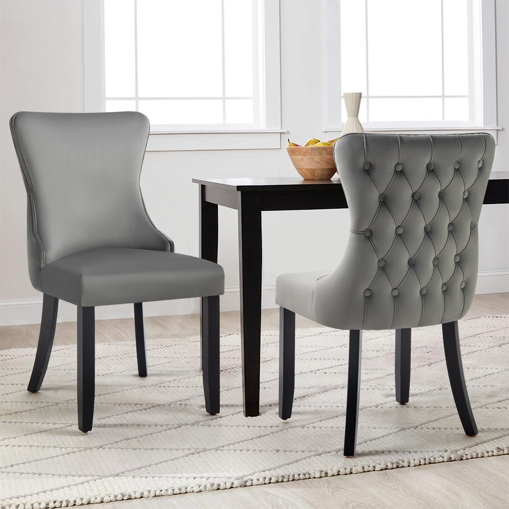 Pair of grey velvet Paris dining chairs with tufted backrest in modern dining setting.