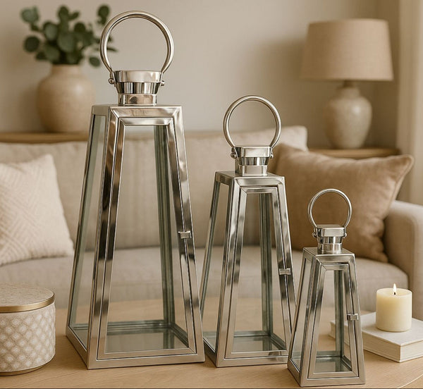 Set of three metallic lanterns on a coffee table with a cozy living room background.