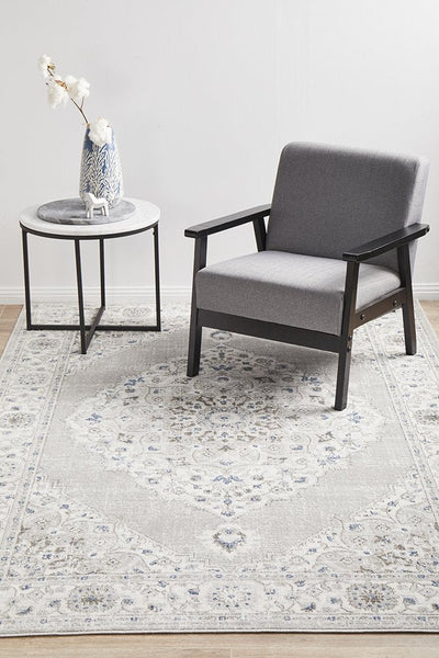 Emotion 77 Silver Rug styled in a modern living room with a grey armchair and side table, adding elegance and serenity to the space.