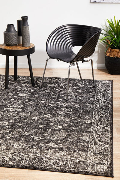 Charcoal rug styled in a modern living room with black chair and side table.
