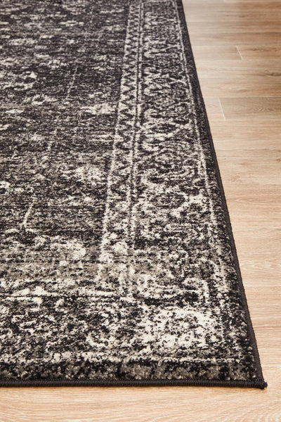 Close-up of charcoal rug edge showing fine weave and detailed pattern.