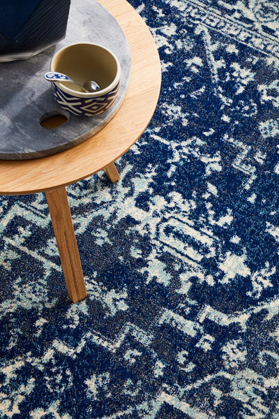 Detailed view of the Evoke 253 Navy Rug with a side table and coffee cup.