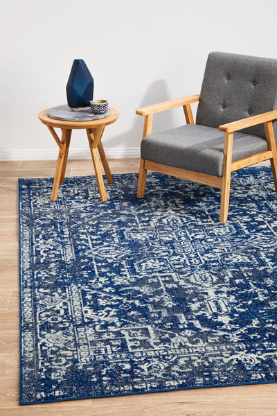 Evoke 253 Navy Rug styled in a modern living room with a wooden armchair and side table.