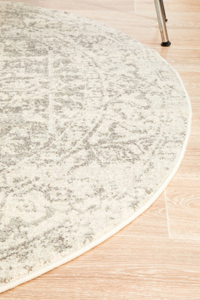Curved edge of round white silver rug on wooden floor