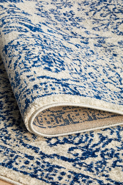 Folded rug edge highlighting navy floral designs, thick pile, and durable woven backing.