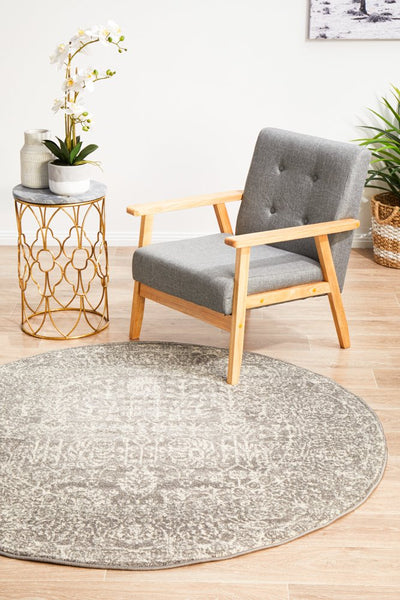 Evoke 256 Grey round rug styled with grey armchair and gold-accent side table.