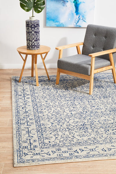 Neutral rug with navy design styled alongside wooden chair and table in modern living room.
