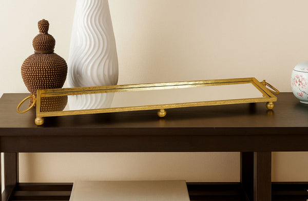 Gold Mirror tray on a wooden table with decorative items against a beige wall