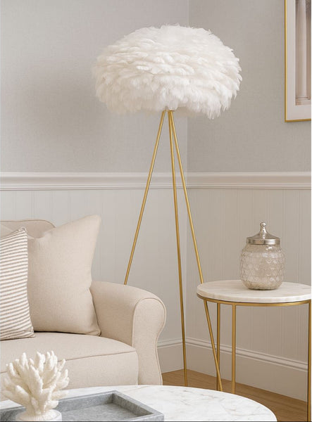 White feathered floor lamp in a living room setting with a beige armchair and side table.