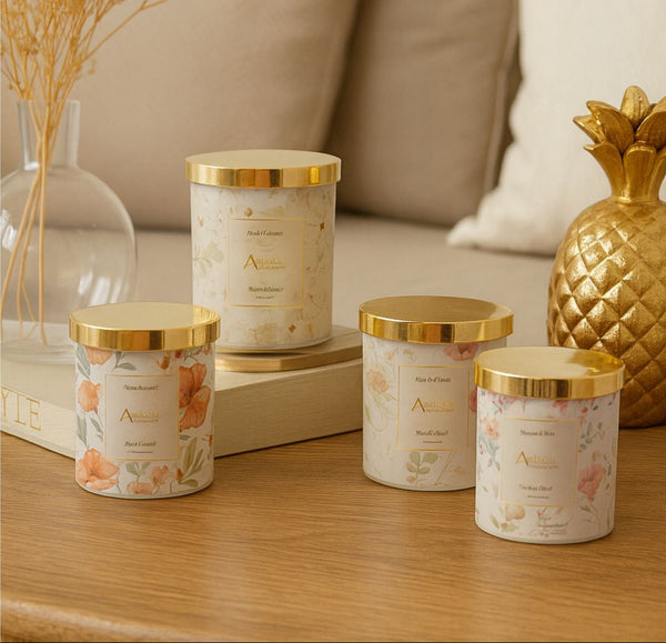 Candles with gold lids on a wooden surface, with decorative elements in the background.