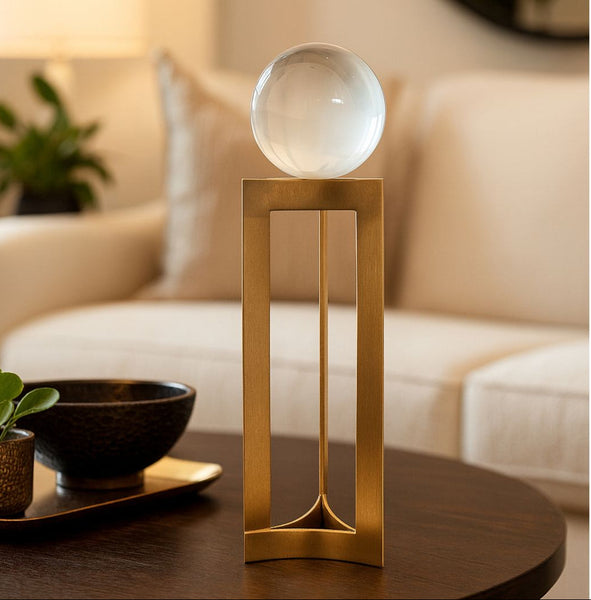 Decorative gold base with a crystal ball on a stand in a living room setting.