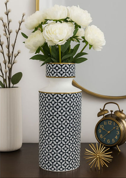 Decorative vase with white flowers on a table next to a clock and another vase.