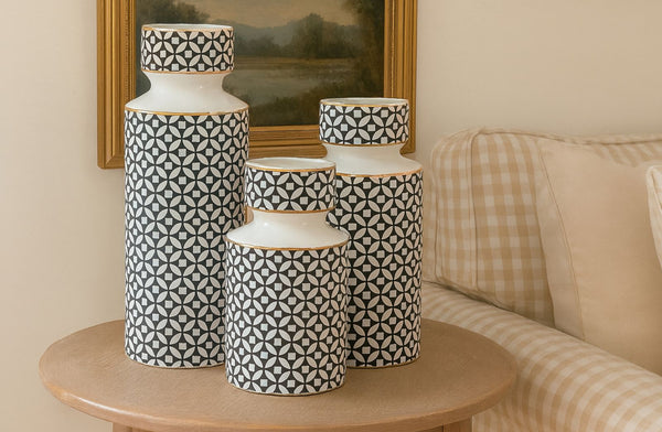 Set of patterned vases on a wooden table with a sofa and framed picture in the background