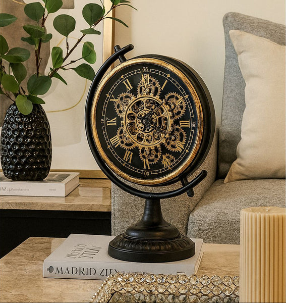 Decorative Black Gear Mechanical table clock on a table with a plant and books in the background