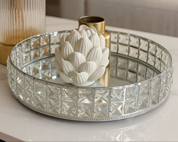 Decorative mirror small silver tray with a white flower sculpture on a reflective surface