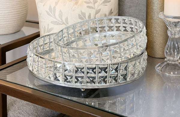 Decorative crystal mirror tray set on a glass table with a candle and decorative items in the background.