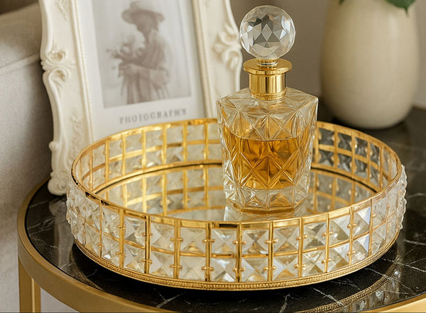 Decorative glass bottle with gold accents on a crystal gold round mirror tray