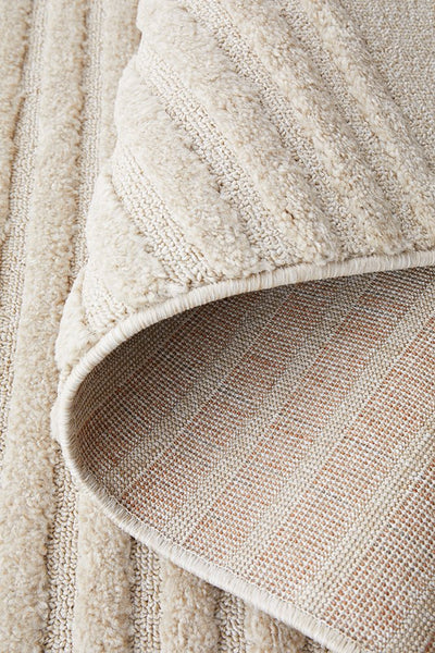 Soft beige rug folded to display durable backing and plush surface texture.