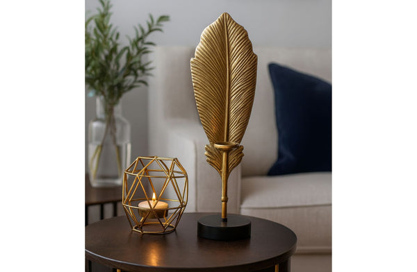 Decorative antique gold leaf sculpture and geometric candle holder on a table with a blurred background