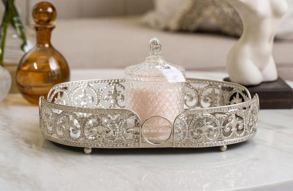 Decorative silver oval tray with a pink candle on a marble surface