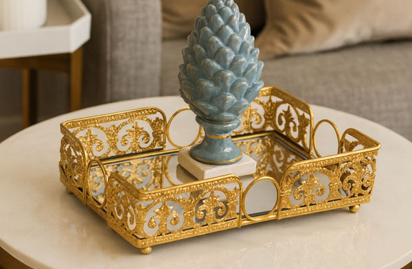 Decorative gold rectangle tray with a blue decorative item on a white surface