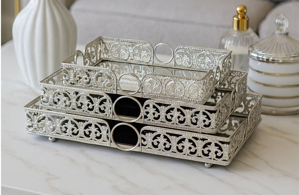 Decorative metal rectangle tray set on a marble surface with decorative bottles in the background.
