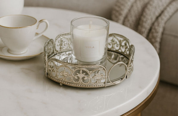 Candle and teacup on a decorative silver round tray on a marble table