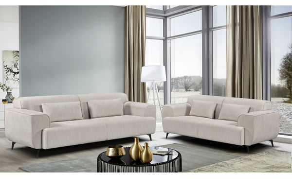 Maddox Lounge Set in beige displayed in a modern living room includes a 3-seater and 2-seater fixed sofa with sleek black metal legs, soft-touch fabric, and matching cushions for a clean, contemporary aesthetic.