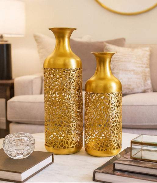 Two gold decorative vases on a table with a living room background