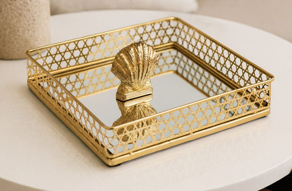 Gold decorative small tray with a shell design on a white surface