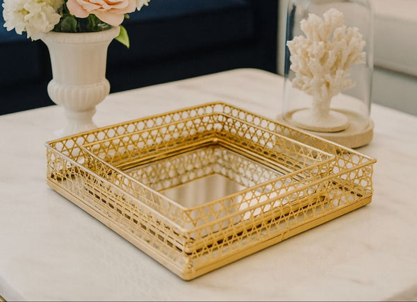 Gold decorative rectangle tray set on a table with floral and coral decorations in the background