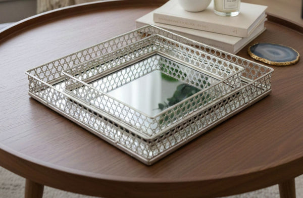 Decorative metal mirror tray set on a wooden table with books and a candle