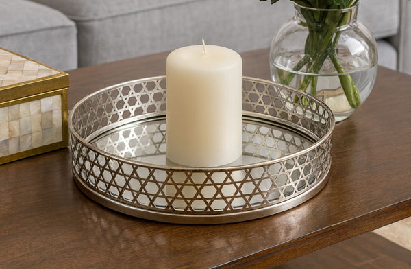 Decorative silver round tray with a candle and vase on a wooden table