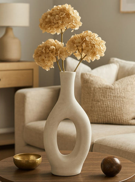 White vase with beige flowers on a wooden table in a living room setting